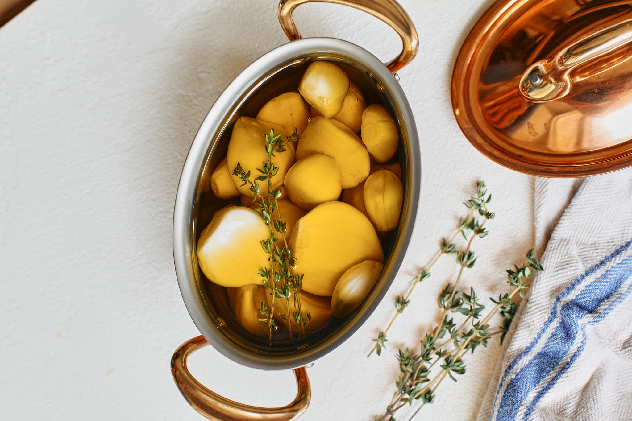 garlic cloves submerged in olive oil with fresh thyme