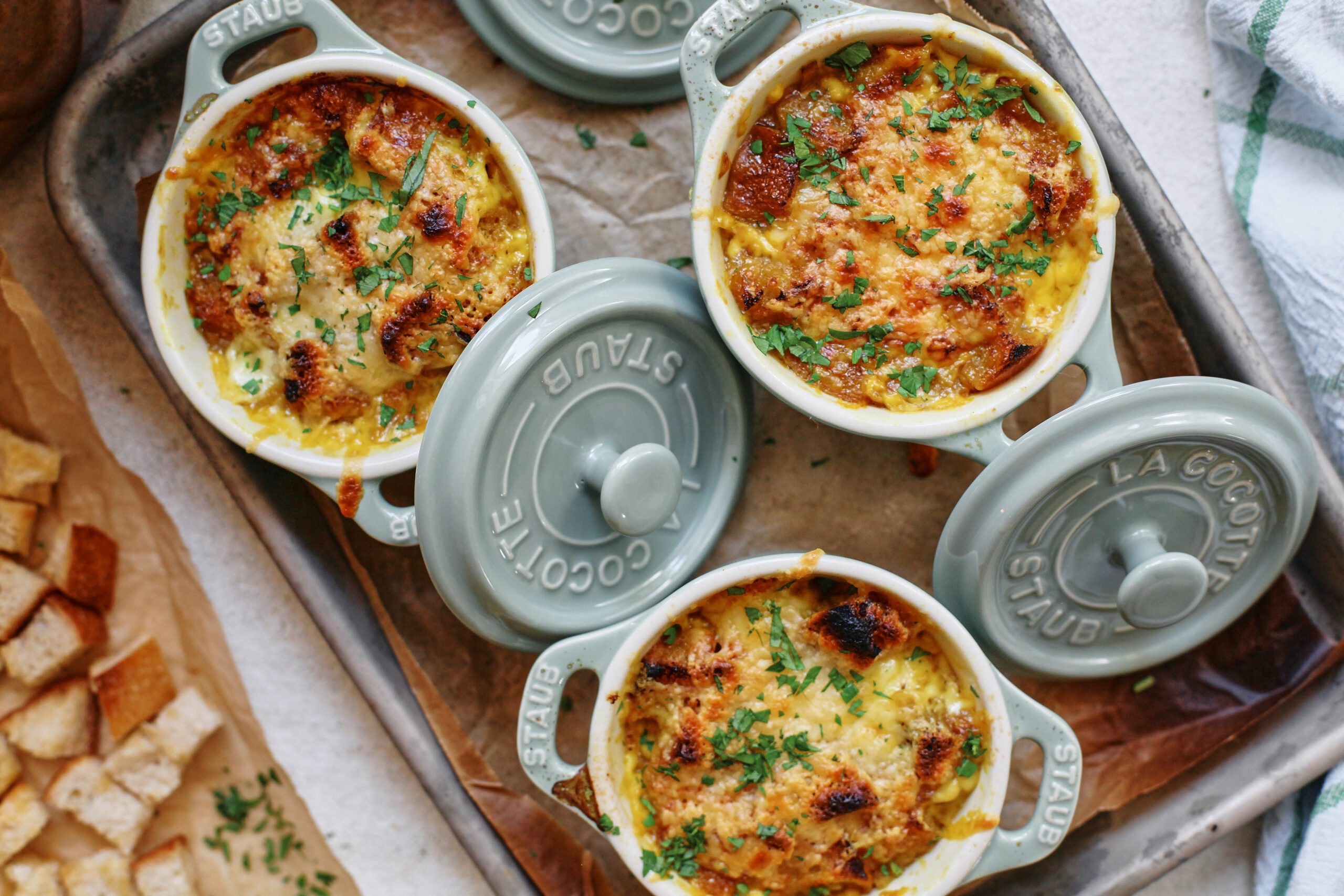 crocks of golden garlic soup after being broiled