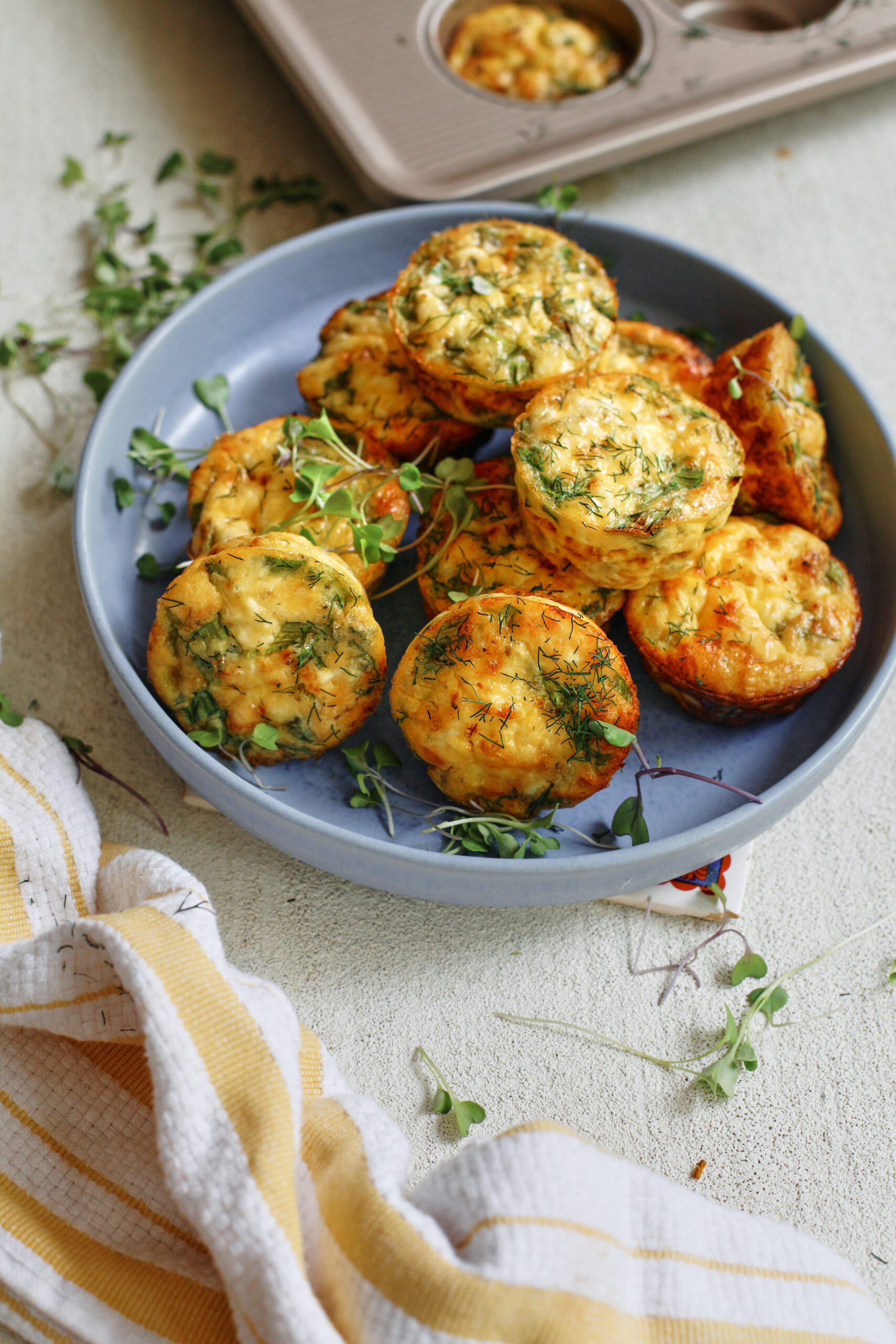 mini spring frittata bites in a blue serving bowl, topped with micro greens