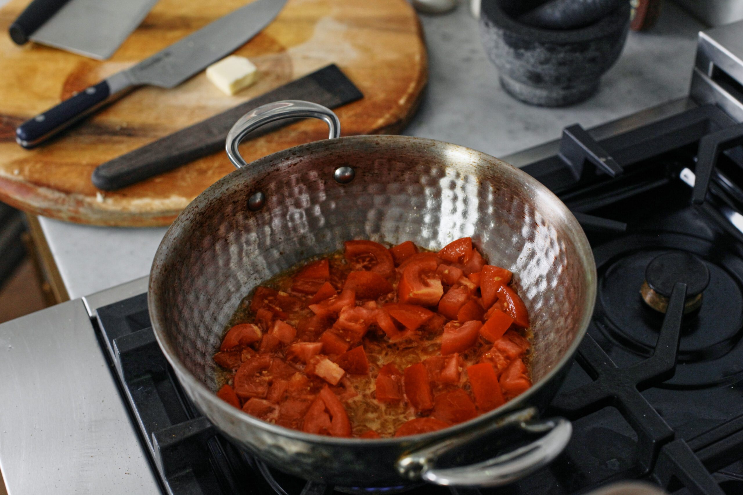 tomatoes sauteeing in butter in a pan on the stove