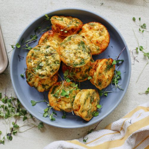 mini spring frittata bites in a blue serving bowl, topped with micro greens