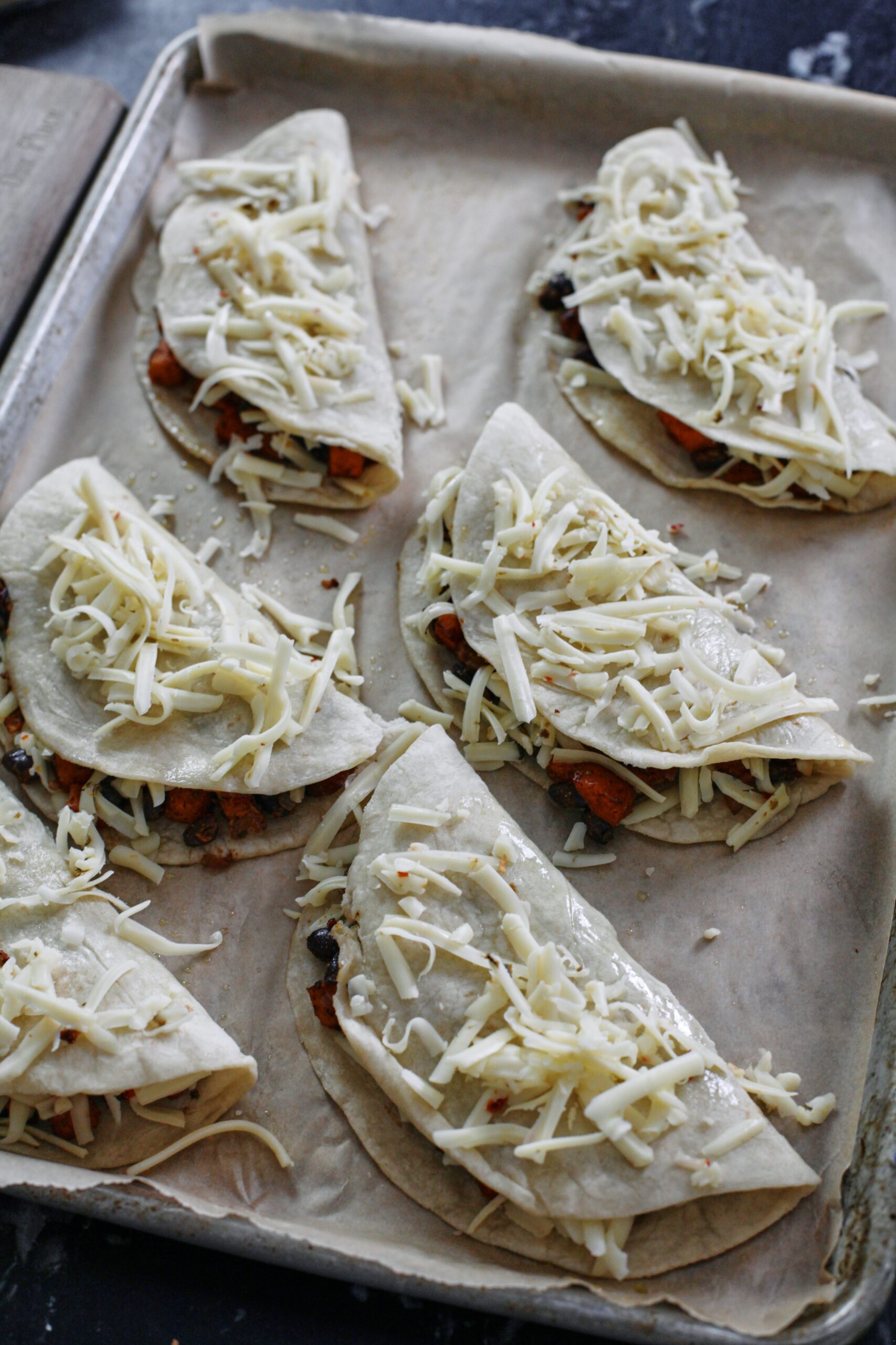 sheet pan tacos topped with cheese before baking