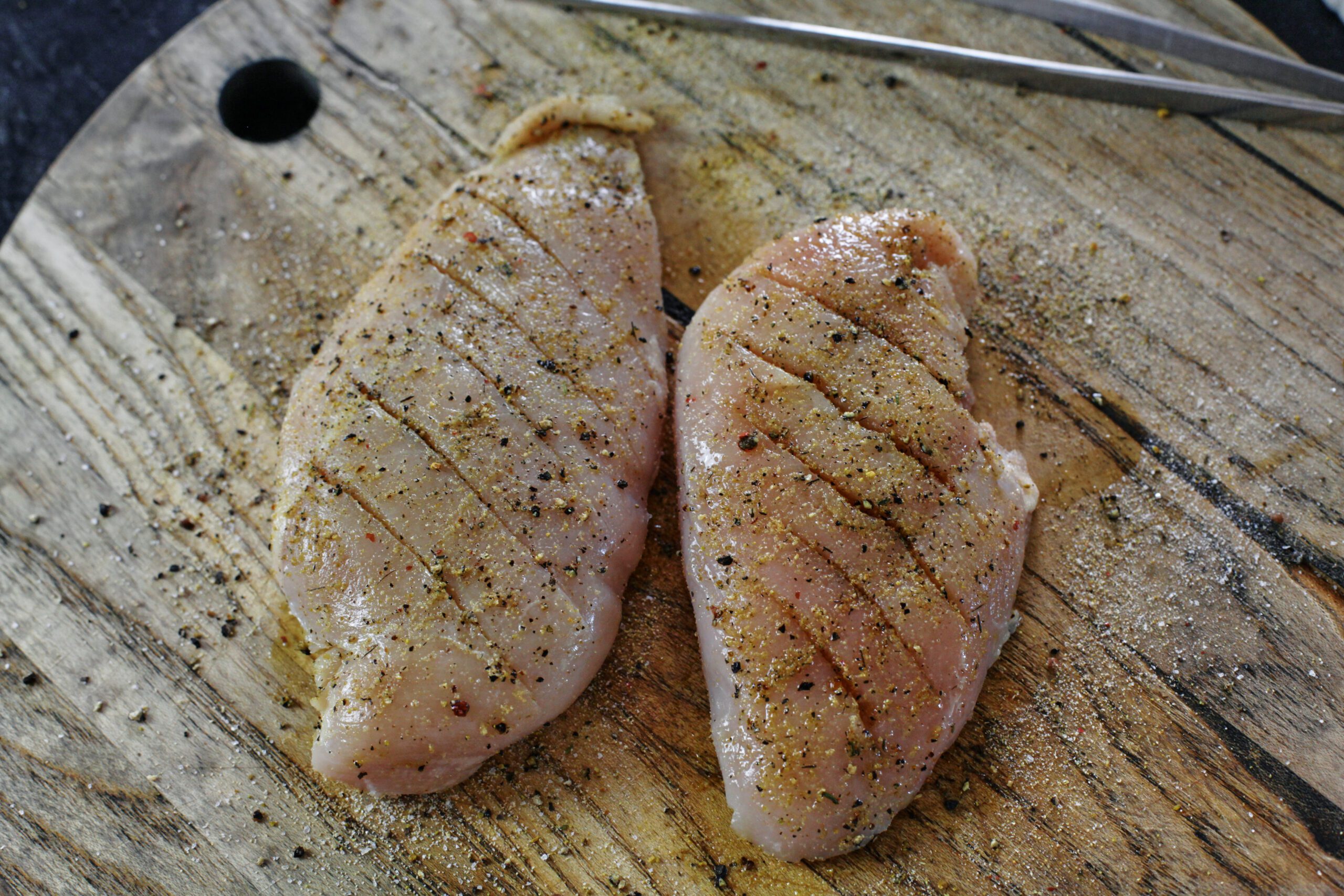 raw chicken breast, sliced along the top, with olive oil and seasonings