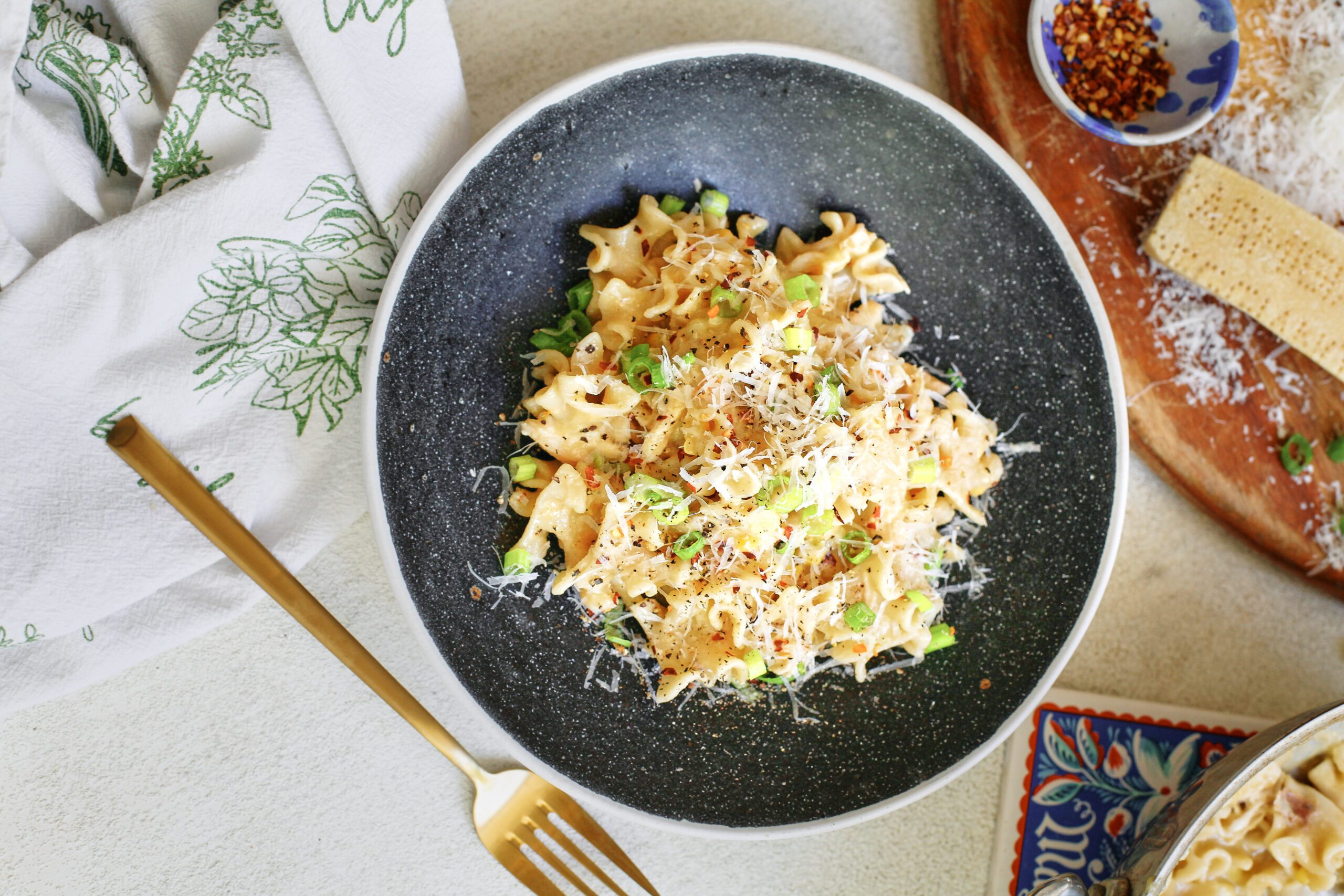 creamy corn and chicken pasta in a charcoal-coloured bowl with a gold fork