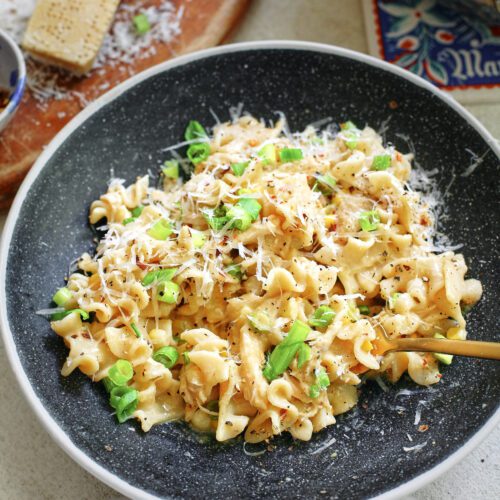creamy corn and chicken pasta in a charcoal-coloured bowl with a gold fork