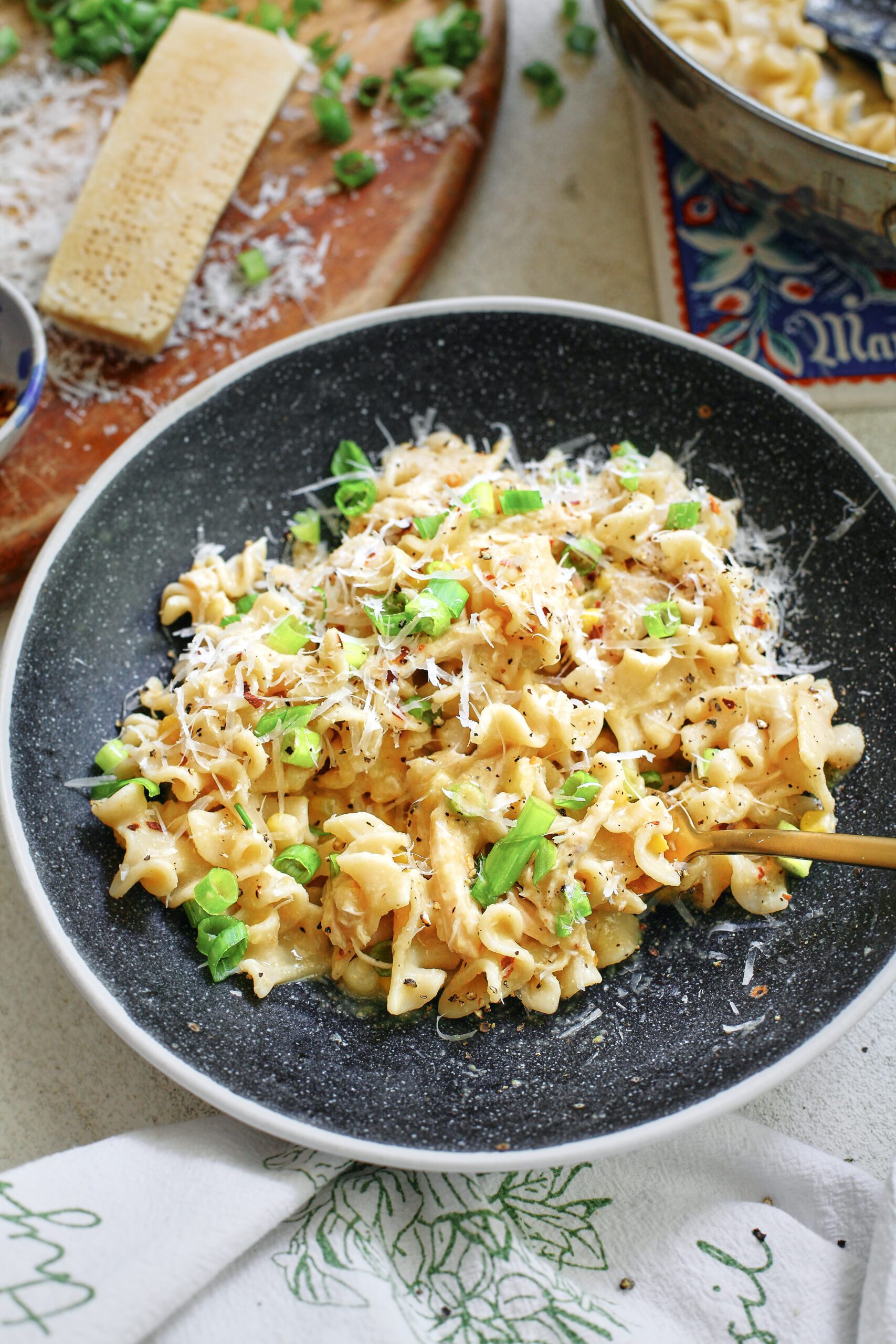 creamy corn and chicken pasta in a charcoal-coloured bowl with a gold fork