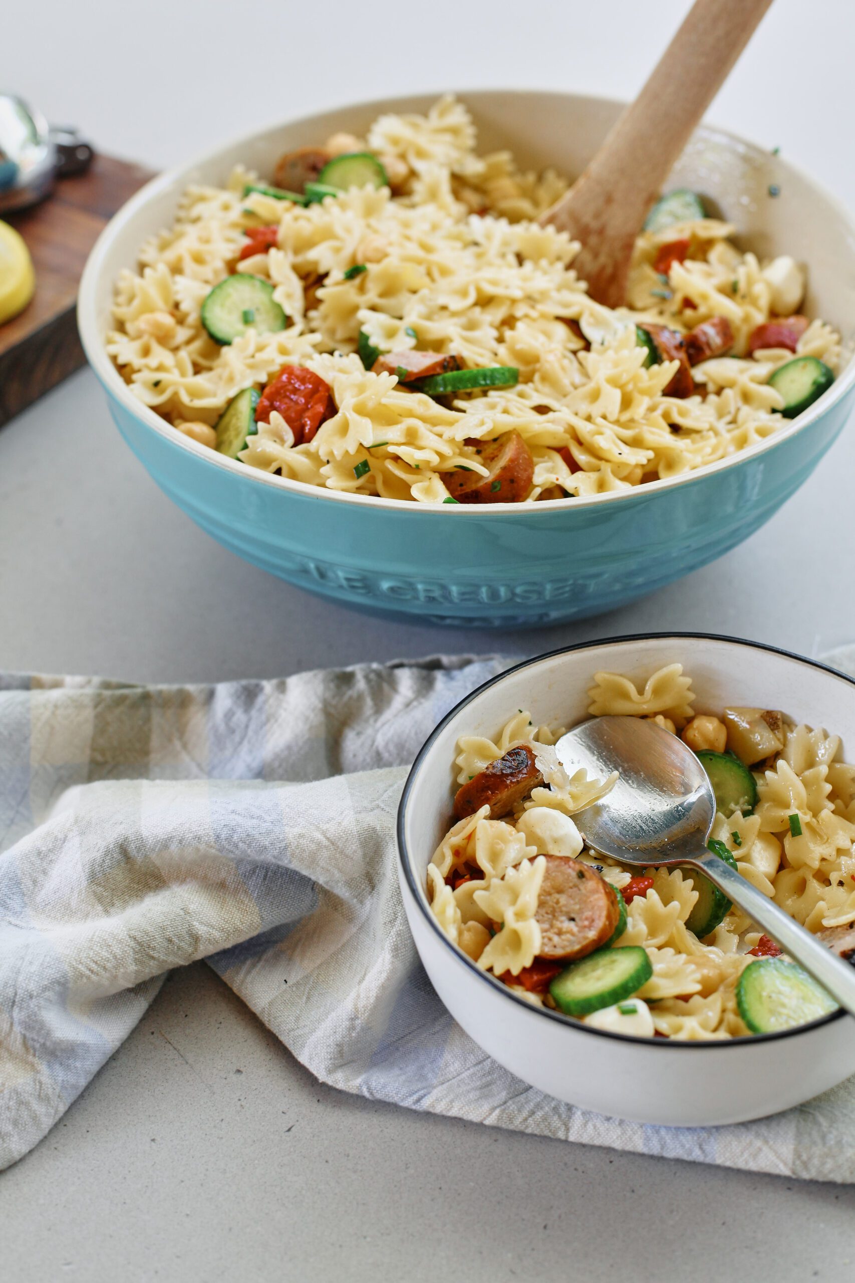 high protein pasta salad in a large bowl, with a serving in a smaller bowl in front