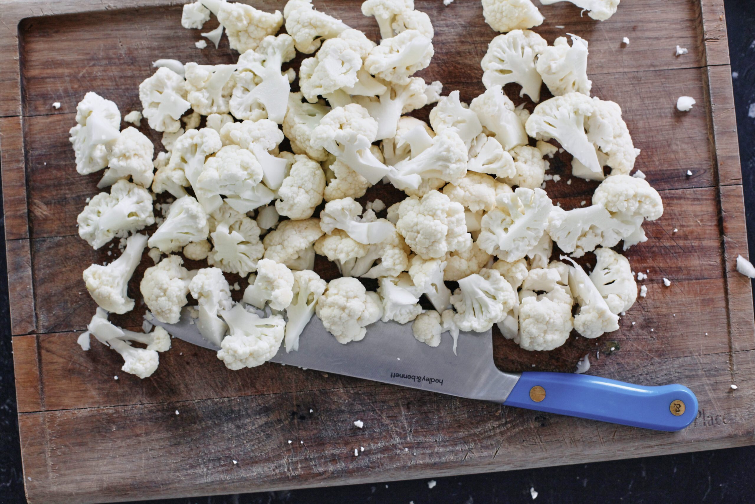Salt and Vinegar Cauliflower chopped cauliflower on a wooden cutting board with a knife