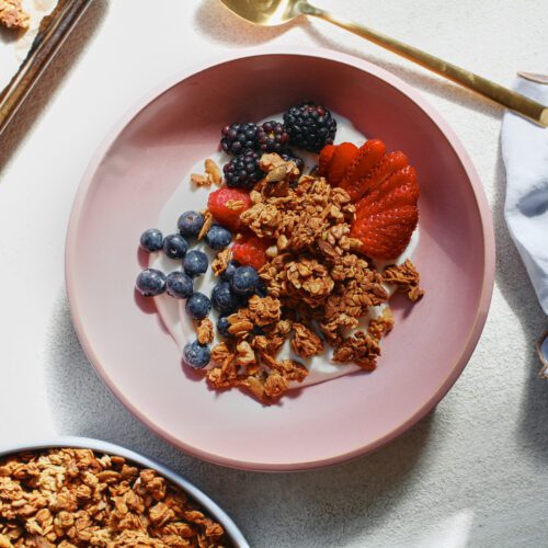sourdough discard granola in a bowl over yogurt and berries