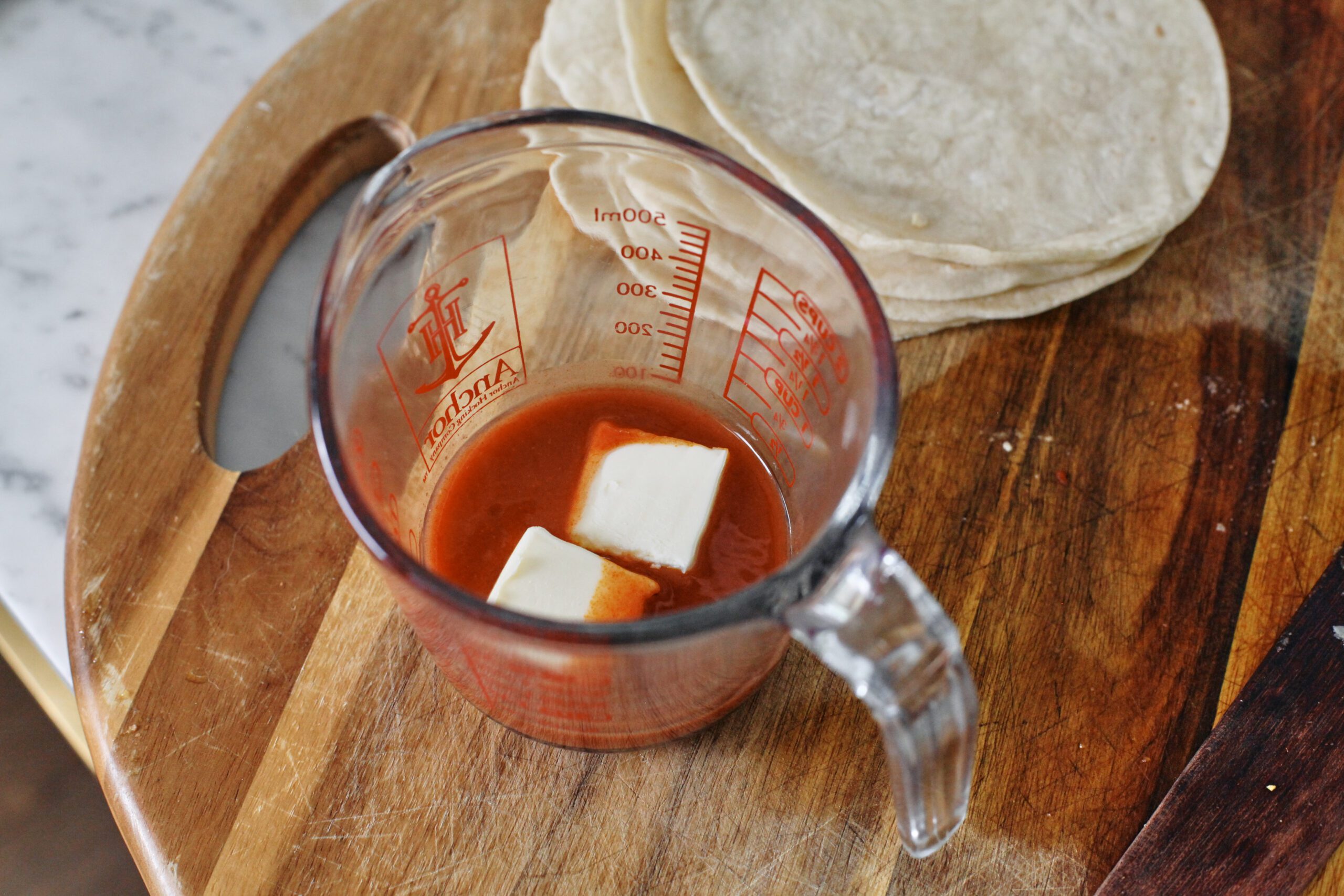 hot sauce and two knobs of butter in a glass measuring cup