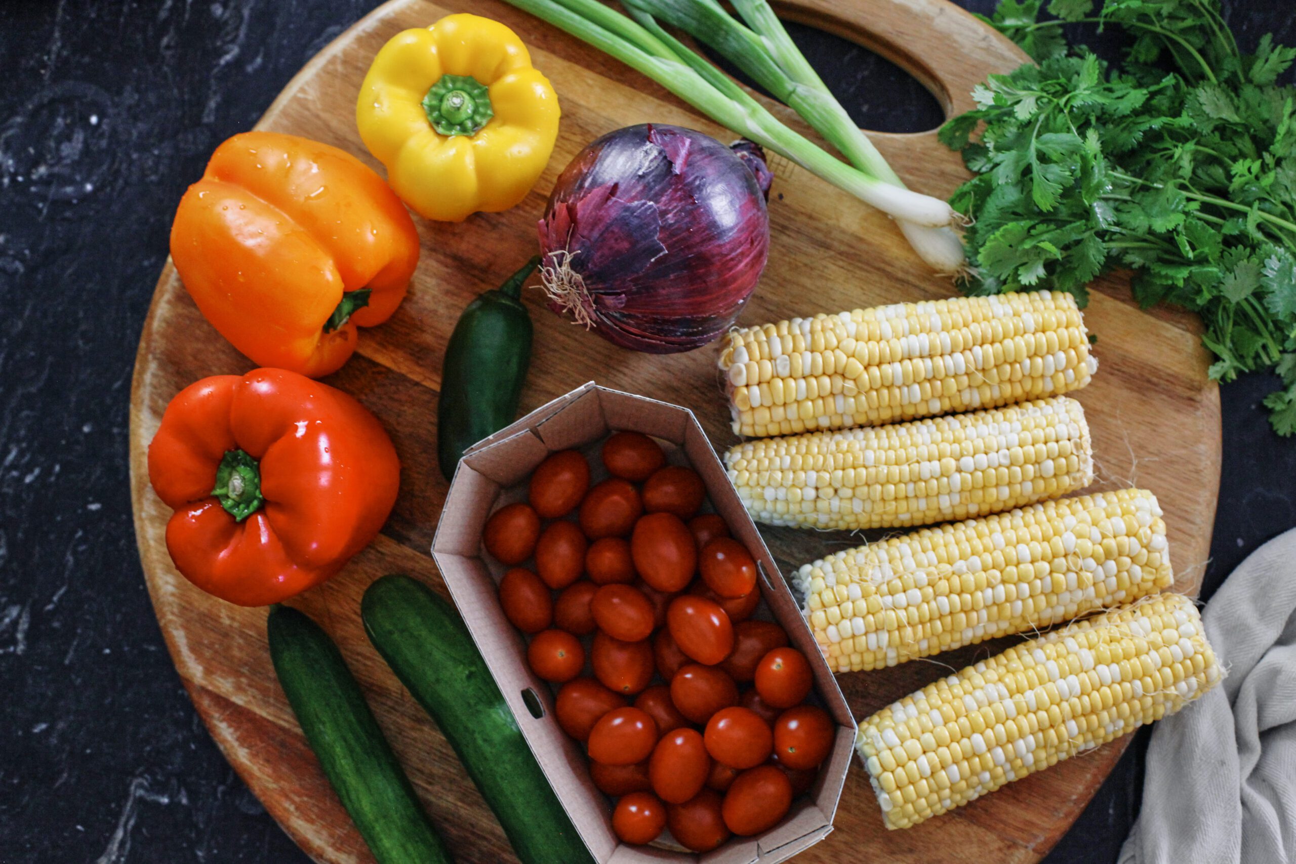 produce for cowboy caviar pasta salad: bell peppers, cucumber, jalapeno, red onion, corn on the cob, cherry tomatoes, green onions, cilantro