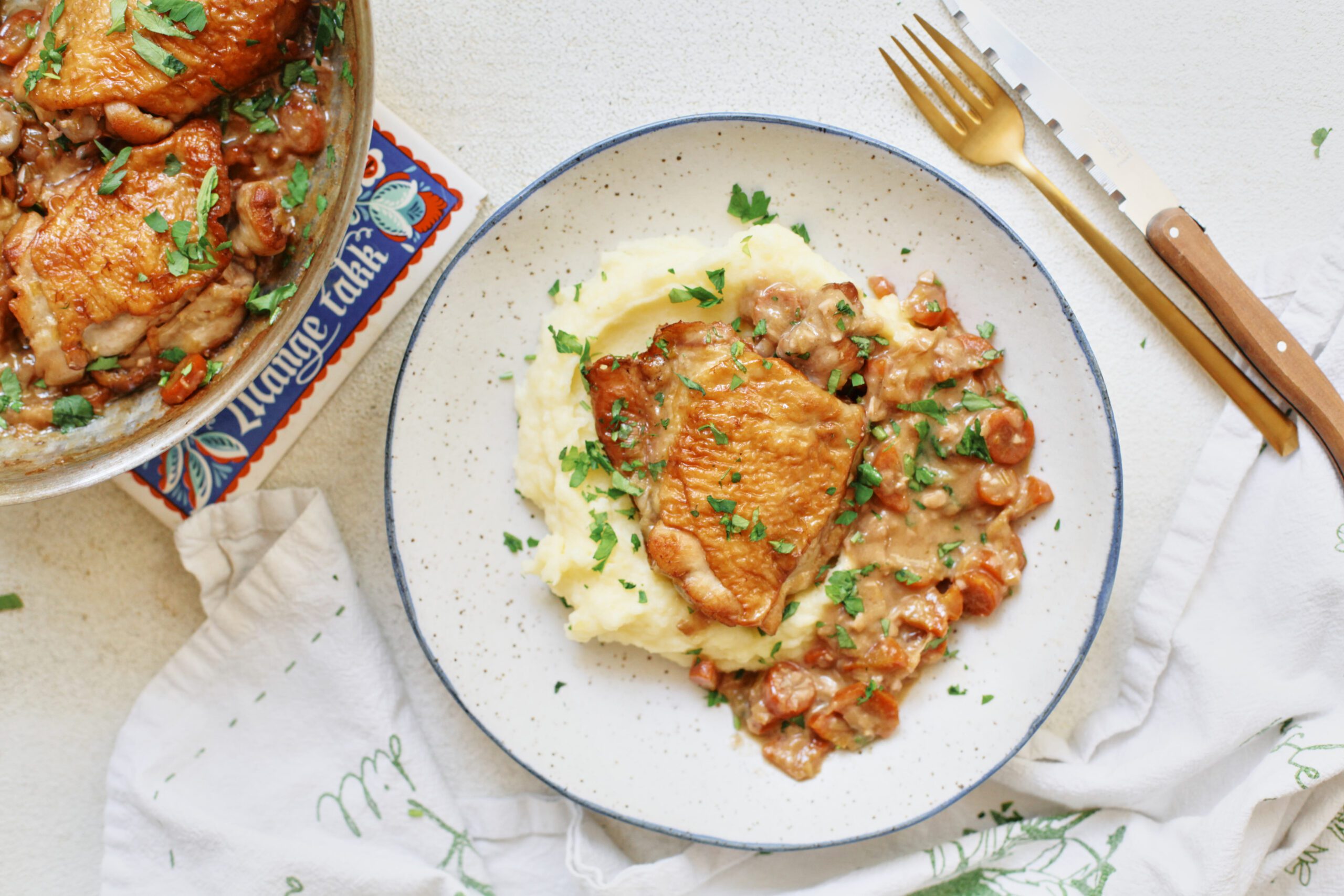 plated coq au vin blanc over a bed of creamy mashed potatoes with fresh Italian parsley on top