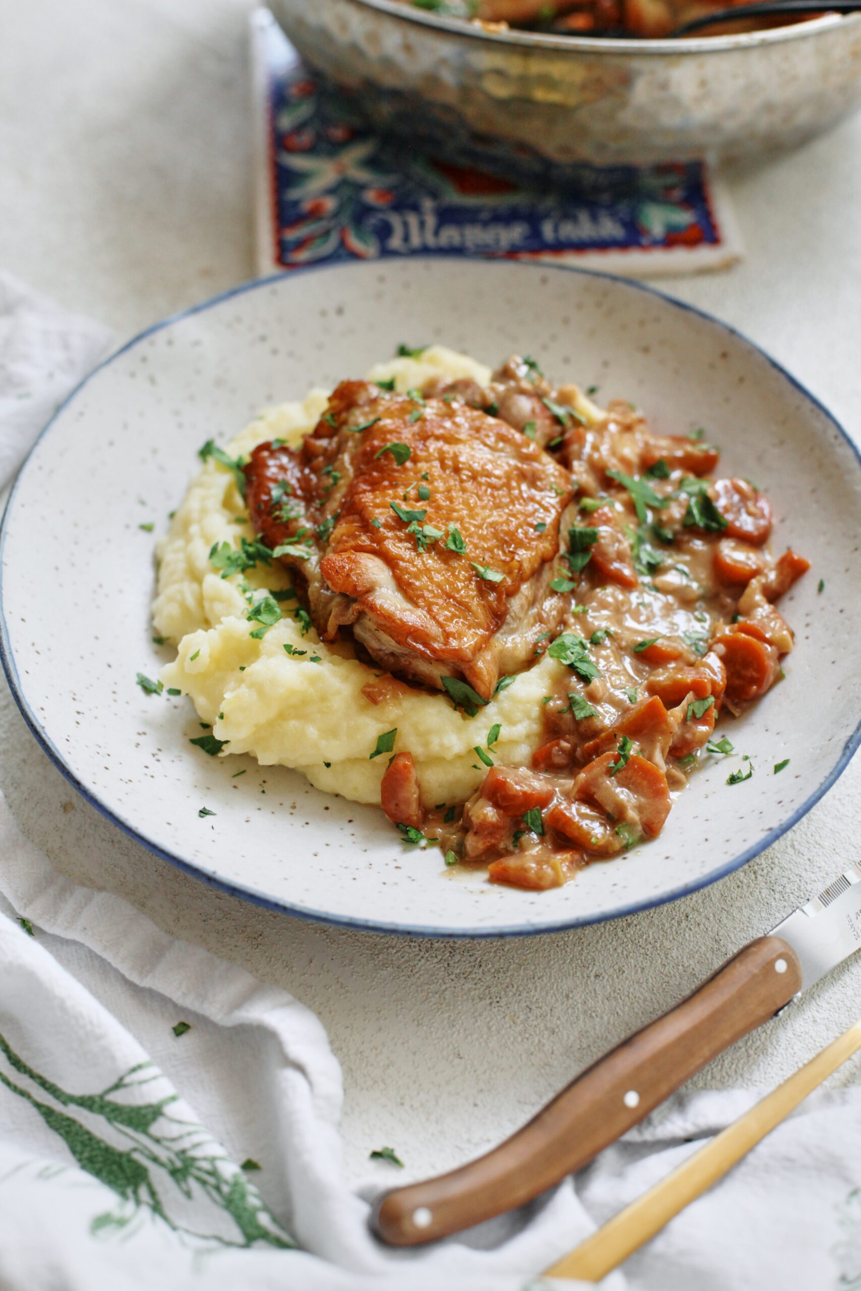plated coq au vin blanc over a bed of creamy mashed potatoes with fresh Italian parsley on top