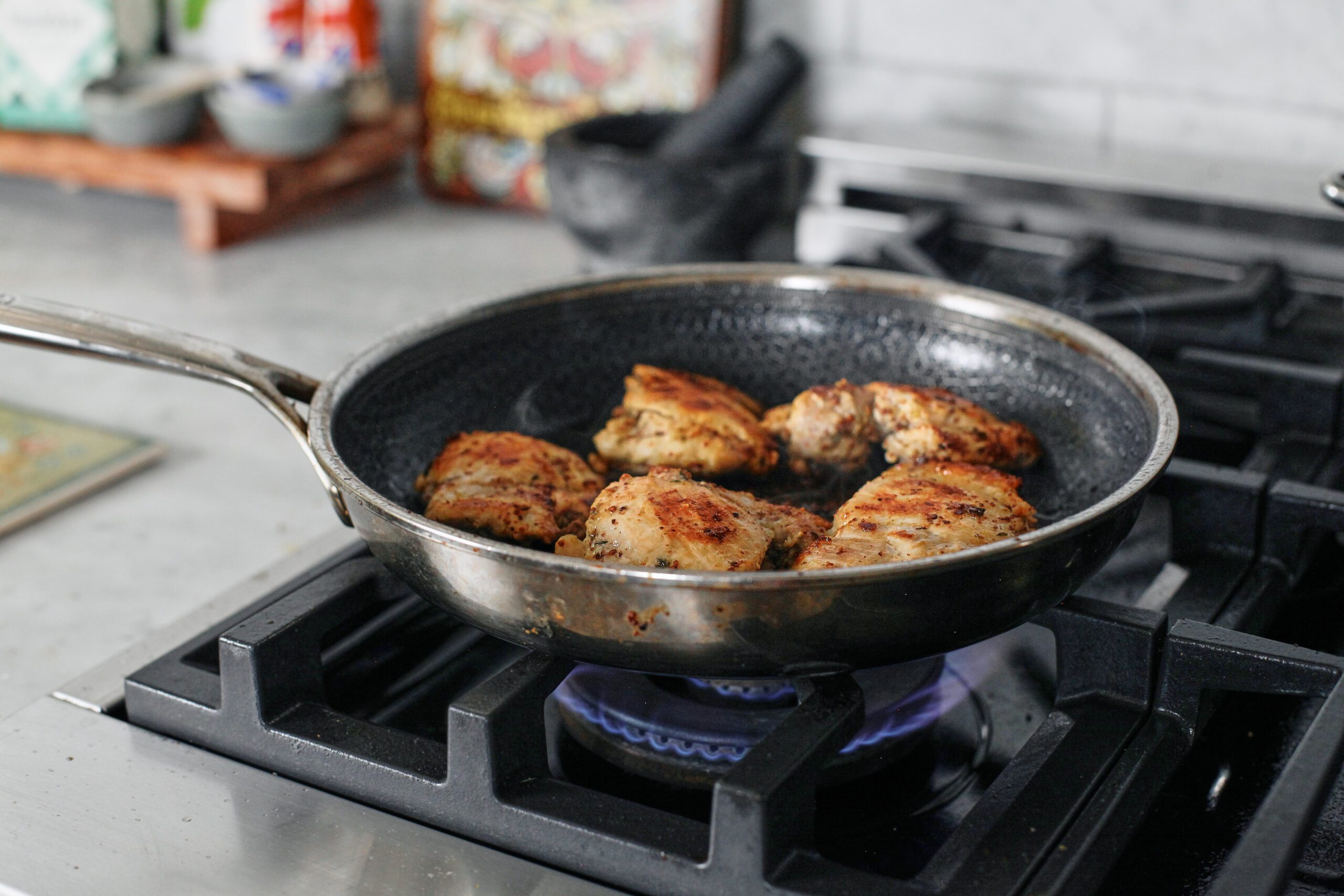 chicken thighs searing in a skillet