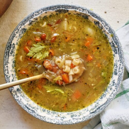 pesto minestrone soup in a white and blue floral-patterned bowl