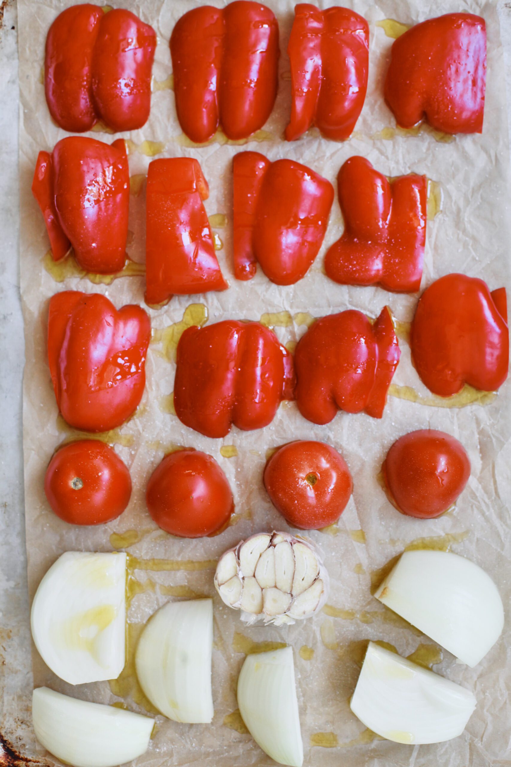 Roasted Red Pepper White Bean Soup 2 red bell peppers, tomatoes, an onion, and a head of garlic arranged on a baking sheet before being roasted