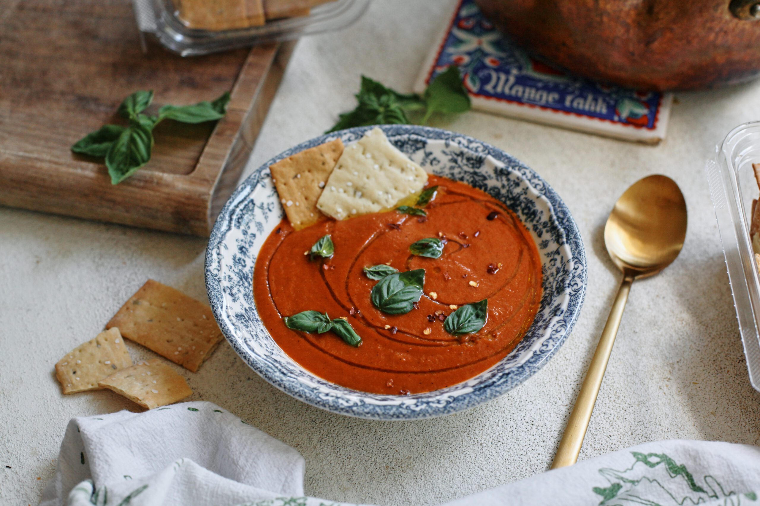 Roasted Red Pepper White Bean Soup 7 Roasted Red Pepper & White Bean Soup in a white bowl with a blue floral pattern, garnished with basil, olive oil, red pepper flakes, and Firehook Rosemary Sea Salt Crackers