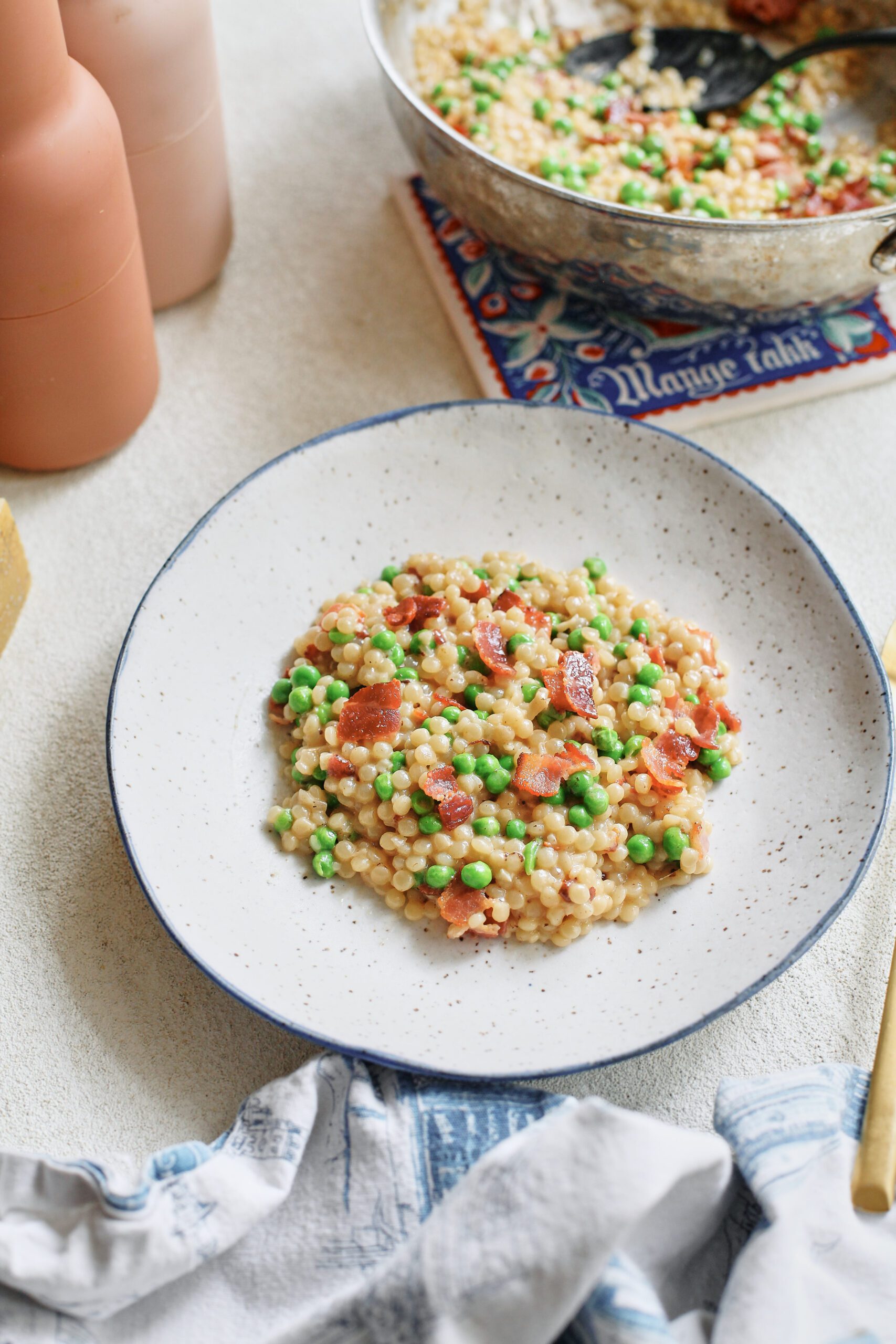 pearl couscous with bacon & peas served into a white bowl