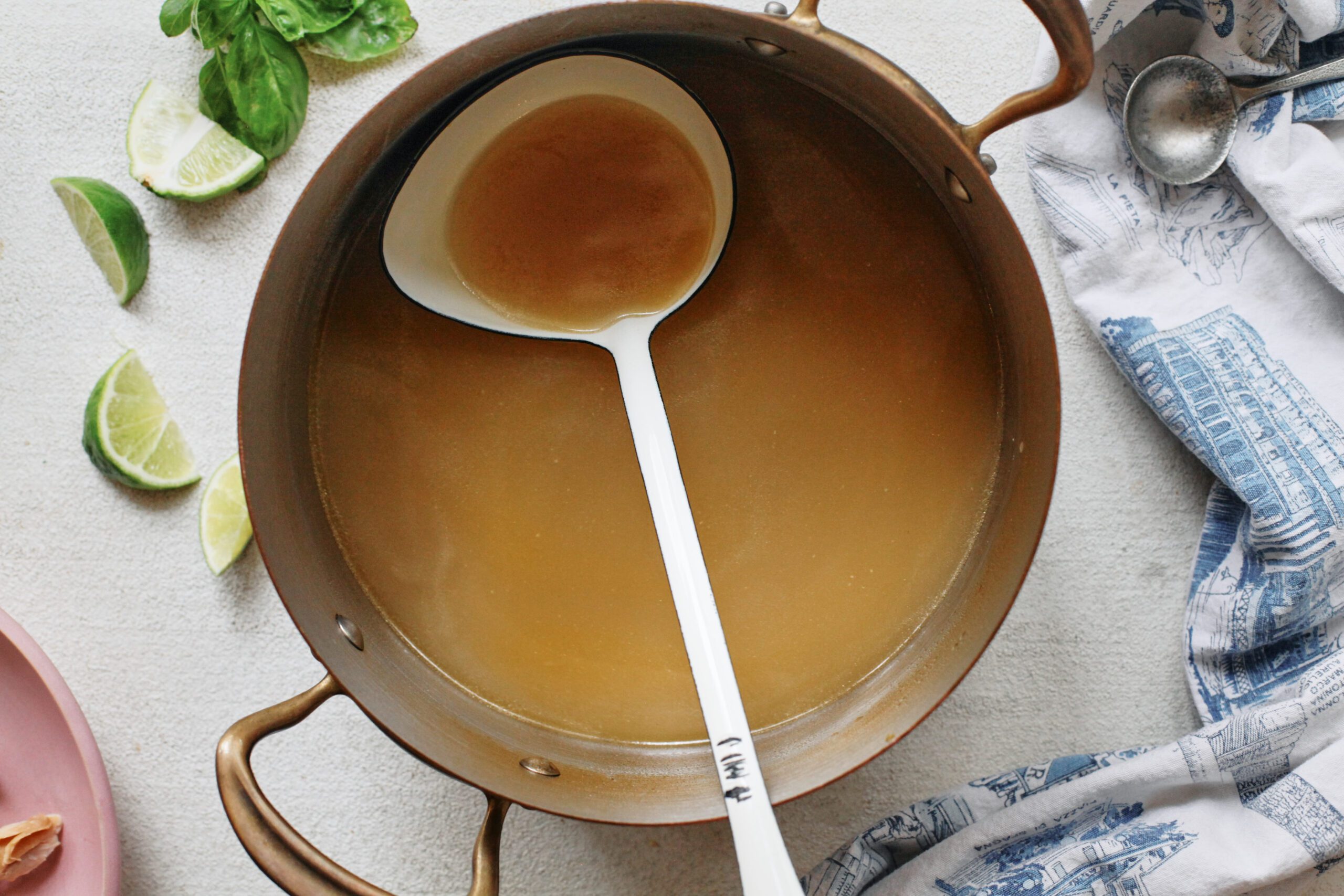 a large pot of broth with a white ladle