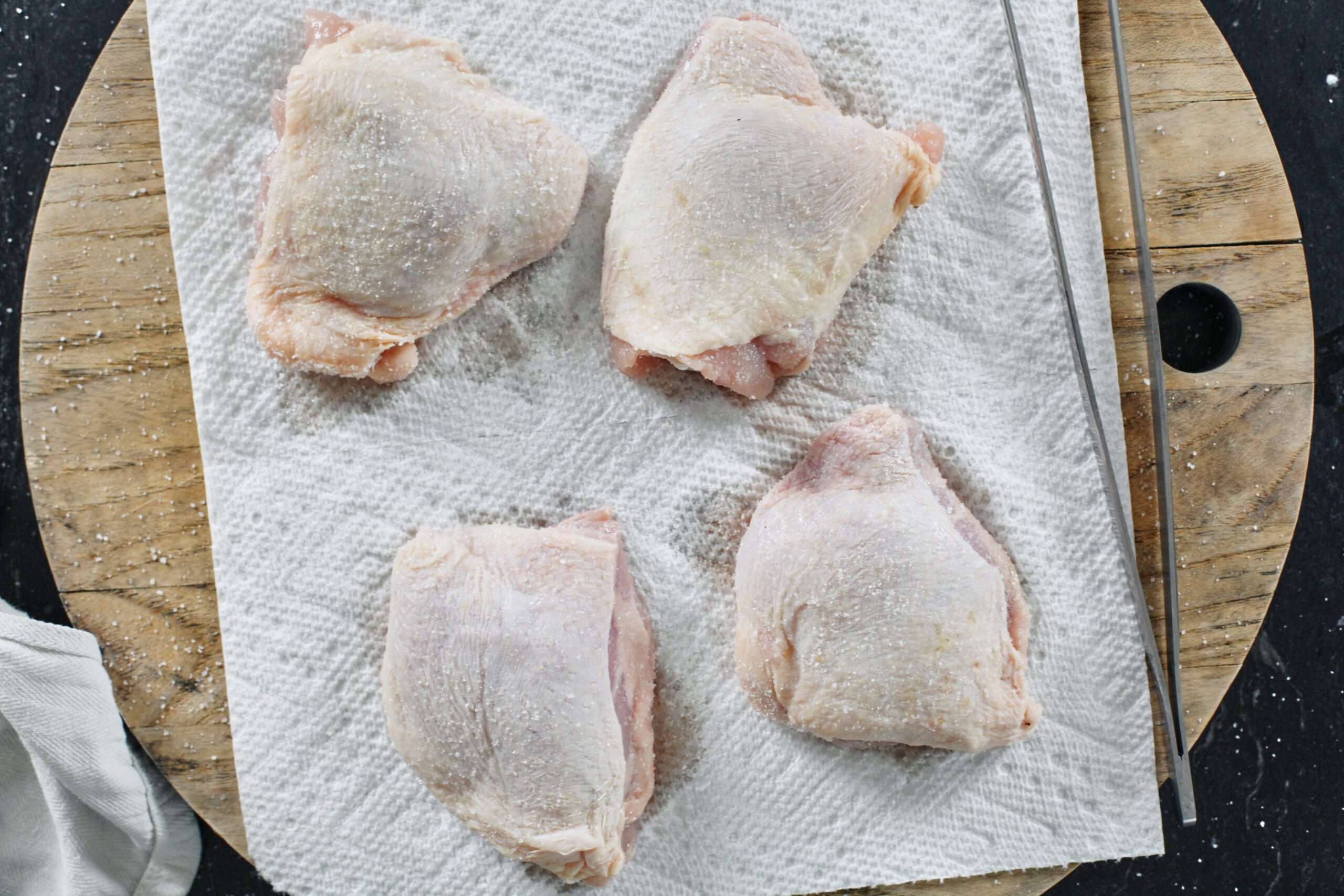 4 skin-on chicken thighs on a paper towel, salted